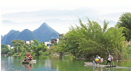 阳朔县金宝乡水库移民手持竹竿撑竹排载着游客悠然穿行在山水间.jpg